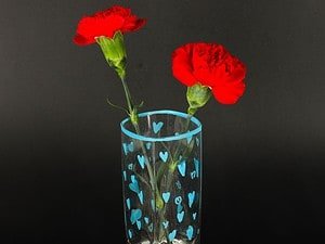 1. vază cu flori roșii de buzunar și inimioare albastre pe fundal negru.