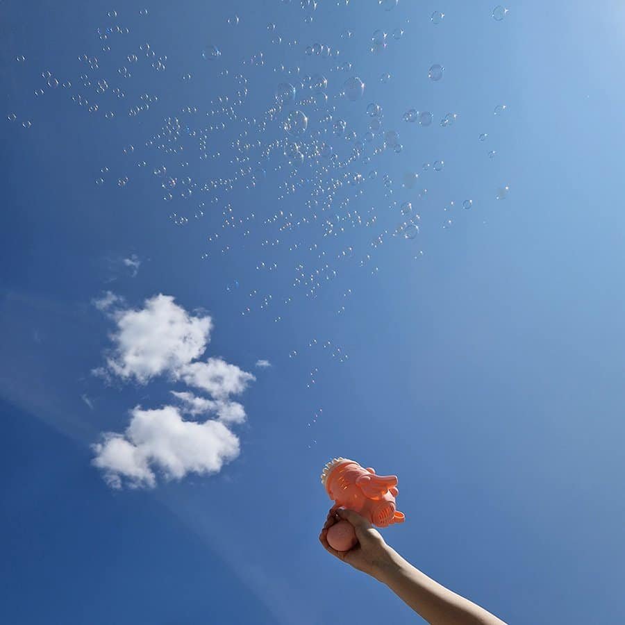 Baloane de săpun, cer albastru, jucarie în mâna pentru copii, distractie în aer liber.