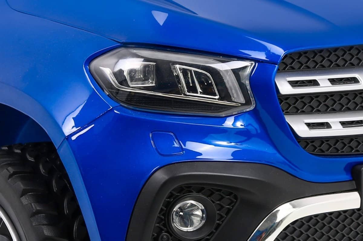 1. Capot de mașină albastră, focalizare pe farul și grila frontală.