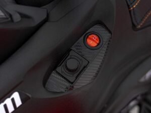Buton rosu de pornire pentru mașini sport, design modern si detalii sportive, elemente de control automobil sportiv.