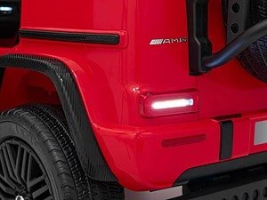 Mașină electrică pentru copii, model Mercedes AMG roșu, detaliu cu roată și far luminos.
