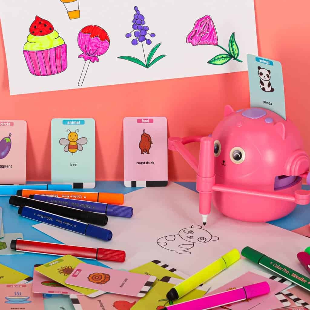 Colorful children's drawing activity with animal and food flashcards, markers, and a cute pig-shaped toy.