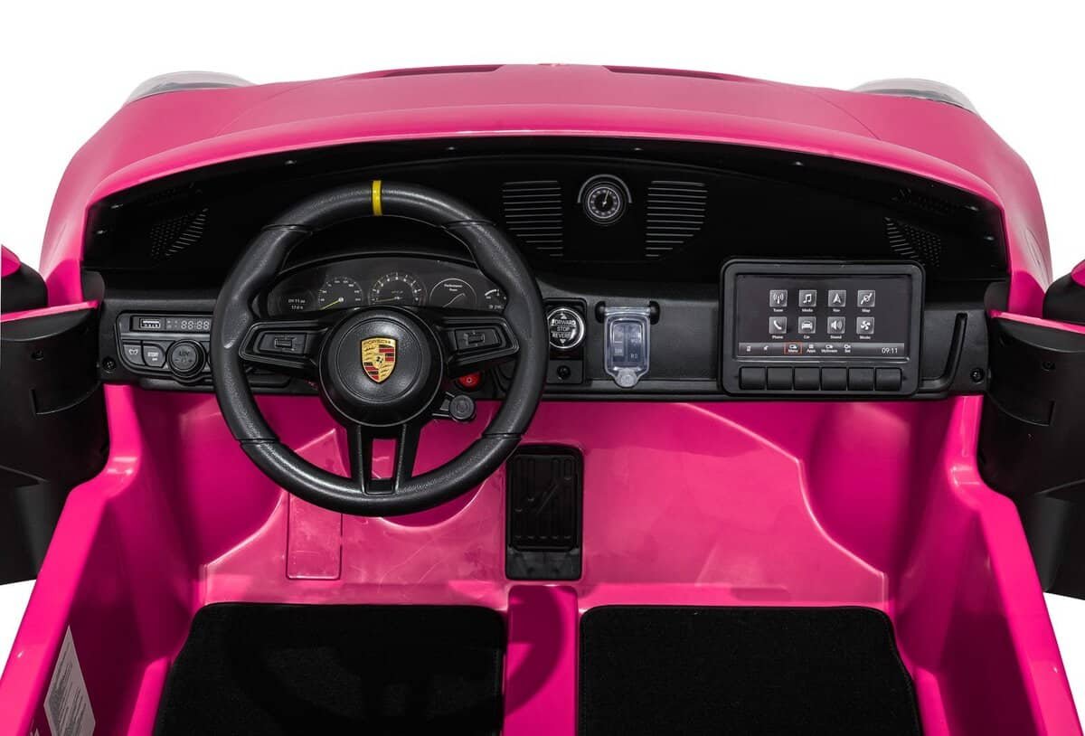 Pink children's ride-on car interior, dashboard, steering wheel, and digital panel.